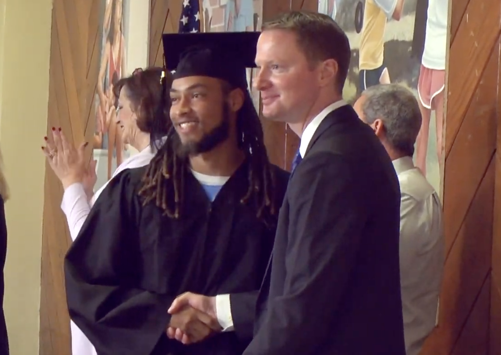 A graduate shaking hands, celebrating achievement